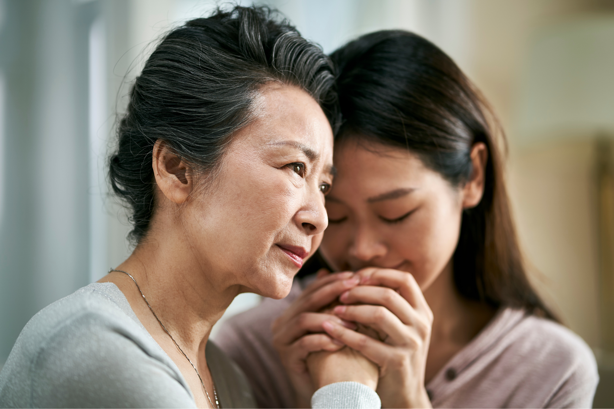 An older woman in the foreground holding hands with a younger woman in the background